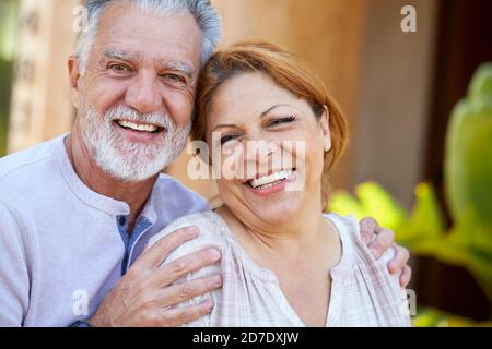 Portrait Of Smiling Senior Hispanic Couple Relaxing In Garden At Home Together Stock Photo