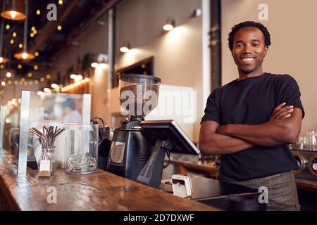 Portrait Of Male Coffee Shop Owner Standing At Sales Desk Stock Photo