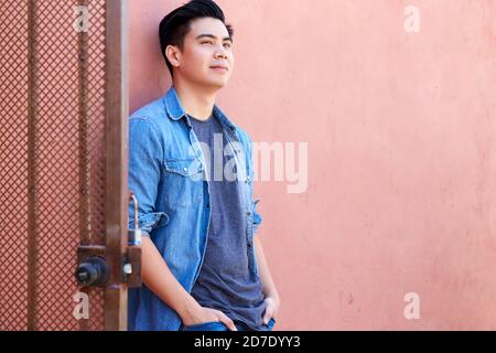 Outdoor Portrait Of Young Man In The Street Leaning Against Wall Stock Photo
