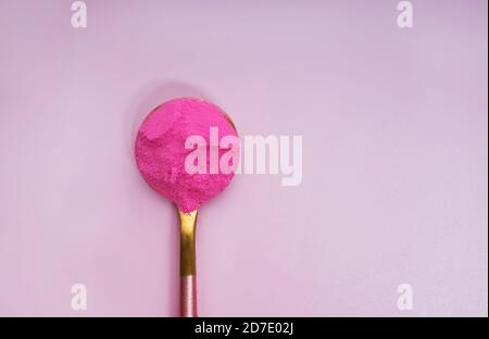 Pink dragonfruit or other superfood powder in a spoon on pink background Stock Photo