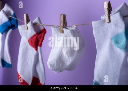 World Prematurity day concept. Normal size and Tiny socks on rope with purple background Stock Photo