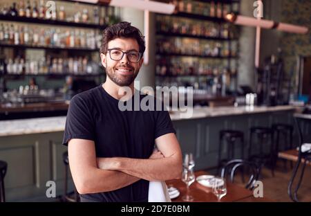 Portrait Of Male Waiter Standing In Bar Restaurant Before Service Stock Photo