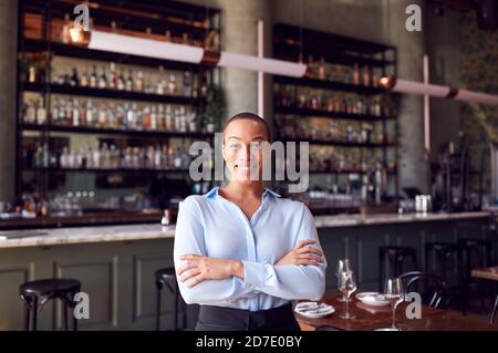 Portrait Of Confident Female Owner Of Restaurant Bar Standing By Counter Stock Photo