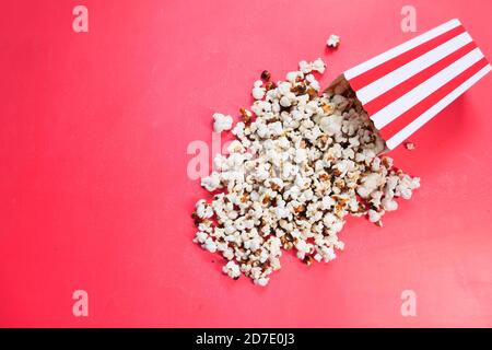 popcorn spilling from a container on red background  Stock Photo