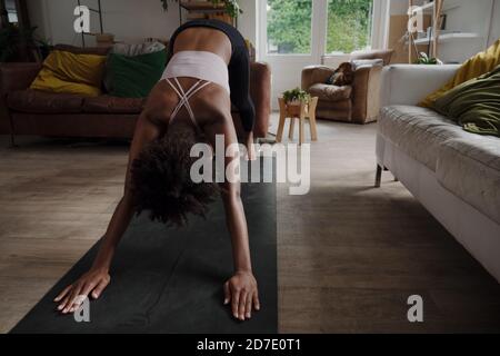 African American female teen in yoga position practising and stretching in modern lounge  Stock Photo