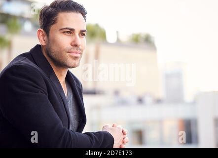 Thoughtful Businessman Standing Outside Office Building With City Skyline In Background Stock Photo