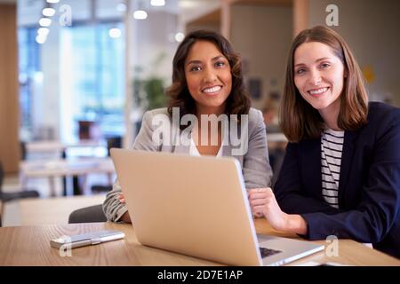 Portrait Of Two Businesswomen With Laptop Collaborating On Project In Office Together Stock Photo
