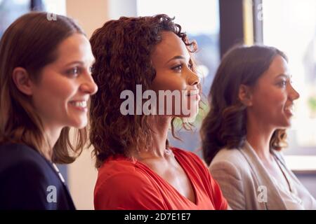 Three Businesswomen Standing In Modern Open Plan Office Together Stock Photo