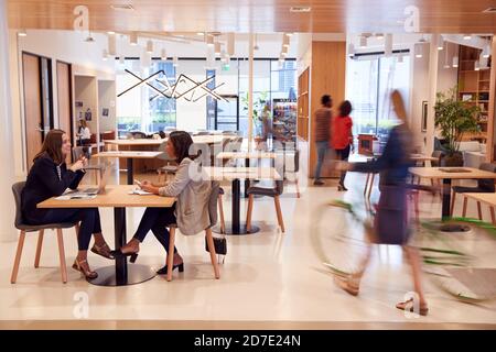 Interior Of Modern Open Plan Office With People Working And Commuters Arriving On Bikes Stock Photo