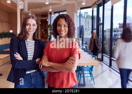 Portrait Of Two Businesswomen Standing In Modern Open Plan Office Together Stock Photo