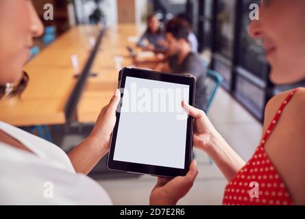 Close Up Of Two Businesswomen Looking At Digital Tablet In Shared Office Workspace Stock Photo