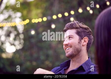 Man In Garden At Home With Friends Enjoying Summer Garden Party Stock Photo