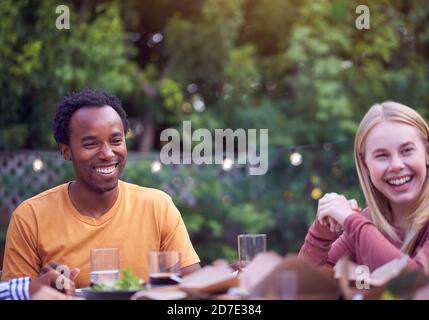 Couple In Garden At Home With Friends Enjoying Summer Garden Party Stock Photo