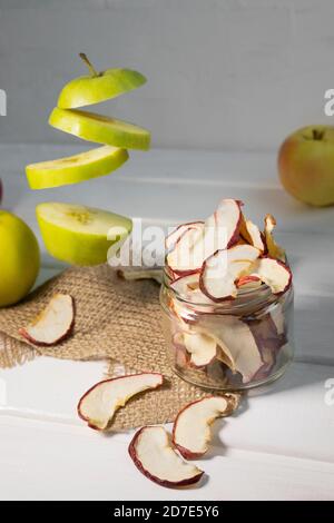 Dried dehydrated apple chips in glass jar with fresh sliced apple on white background Stock Photo