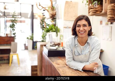 Portrait Of Smiling Female Sales Assistant Standing Behind Sales Desk Of Florists Store Stock Photo