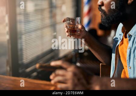 Bearded young man smoking cigar and drinking whisky Stock Photo