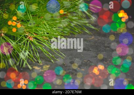 Christmas fir branches on a background of blurred colorful lights with space for text on the left, side view close-up. Template for a postcard, poster Stock Photo