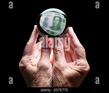 Senior caucasian hands holding a crystal futures or fortune ball reflecting a China 50 Yuan note as concept for the exchange rate for the currency Stock Photo