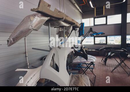 Auto bumper part is installed on the racks after painting in car repair shop. Stock Photo