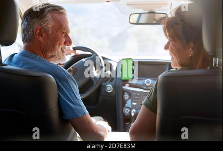 Senior Hispanic Couple On Drive Through Countryside Using Sat Nav On Mobile Phone Stock Photo