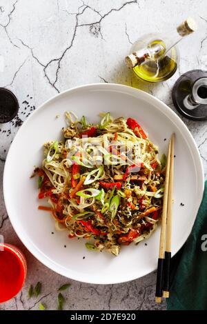 vegan pad thai rice pasta with vegetables and tofu on gray concrete background with soy sauce and sesame oil Stock Photo