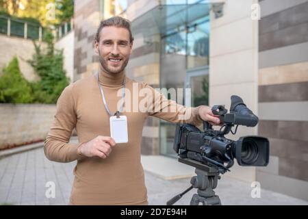 Smiling operator standing near camera in front of modern building Stock Photo