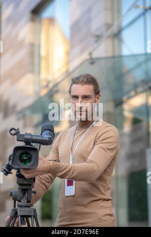 Involved operator standing behind camera, busy with filming Stock Photo