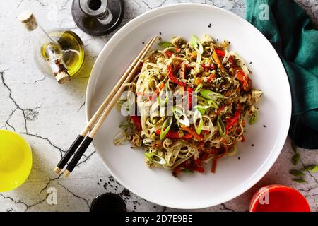 vegan pad thai rice pasta with vegetables and tofu on gray concrete background with soy sauce and sesame oil Stock Photo