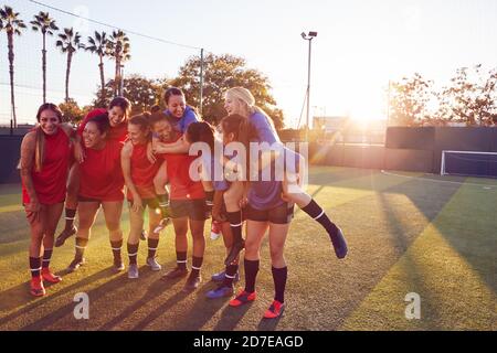 Portrait Of Womens Football Team Relaxing After Training For Soccer Match On Outdoor Pitch Stock Photo