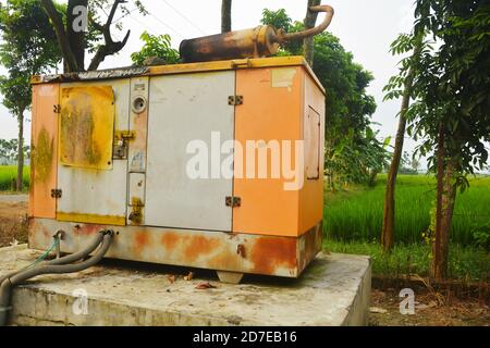 Close up of a old big electric generator set with rusted cover on a raised concrete platform, selective focusing Stock Photo