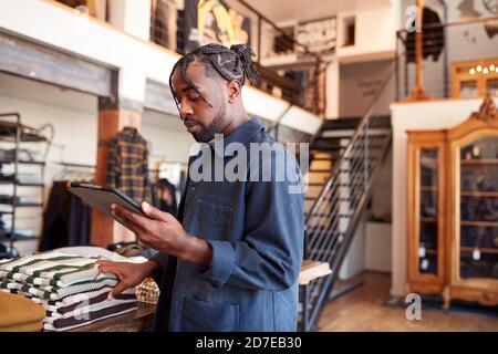 Male Owner Of Fashion Store Using Digital Tablet To Check Stock In Clothing Store Stock Photo