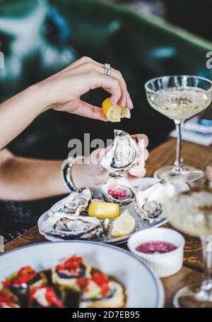 Hands of woman squeezing fresh lemon juice to Irish oyster Stock Photo