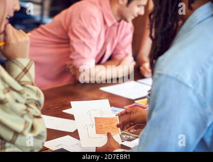 Close Up Of Fashion Designers Having Creative Meeting Around Wooden Table In Studio Stock Photo