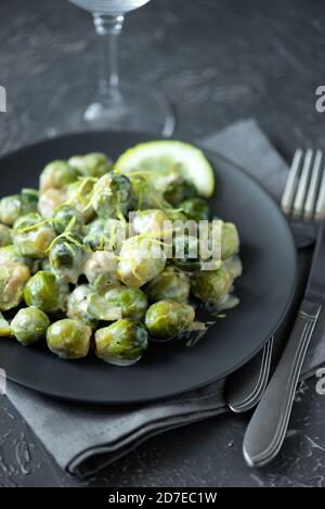 Close-up plate with delicious roasted brussels sprouts on table. Vegetarian food. Selective focus Stock Photo