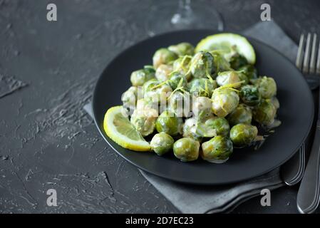 Close-up plate with delicious roasted brussels sprouts on table. Vegetarian food. Selective focus Stock Photo