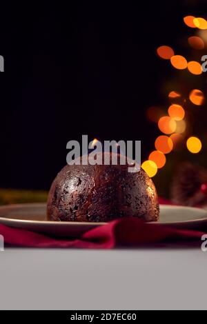 Brandy Soaked Christmas Pudding With Flames On Table Set For Festive Christmas Meal Stock Photo