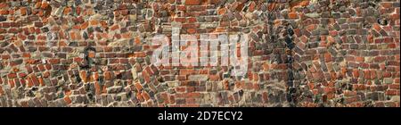 A panoramic section of antique red brick wall with random construction and including wrought iron S anchor plate Stock Photo