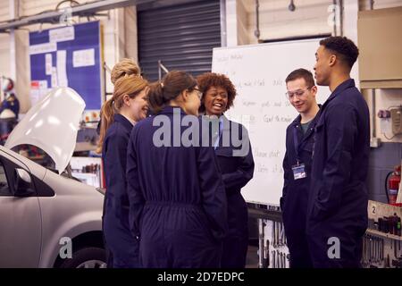 Students Studying For Auto Mechanic Apprenticeship At College Standing By Whiteboard Stock Photo