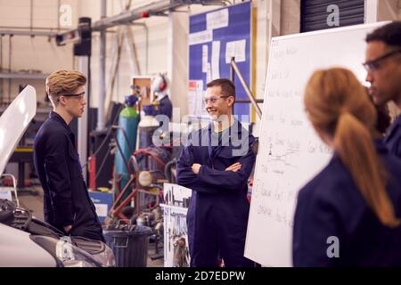 Students Studying For Auto Mechanic Apprenticeship At College Standing By Whiteboard Stock Photo