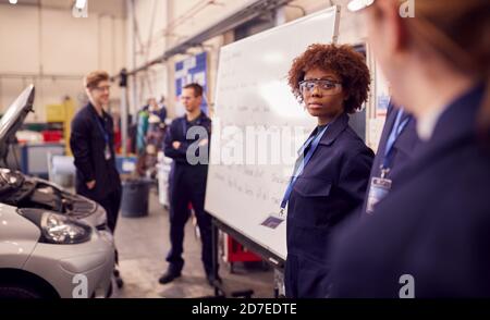 Students Studying For Auto Mechanic Apprenticeship At College Standing By Whiteboard Stock Photo