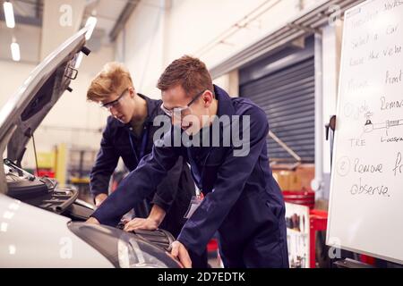 Two Male Students Studying For Auto Mechanic Apprenticeship At College Working On Car Engine Stock Photo