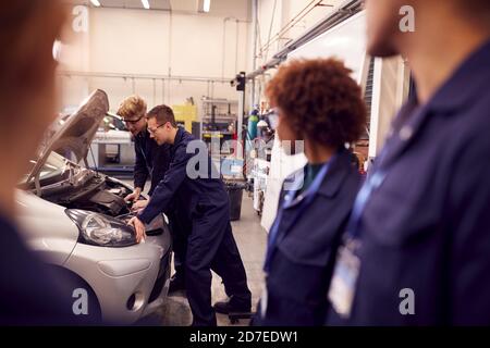 Students Studying For Auto Mechanic Apprenticeship At College Working On Car Engine Stock Photo