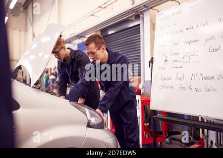 Two Male Students Studying For Auto Mechanic Apprenticeship At College Working On Car Engine Stock Photo
