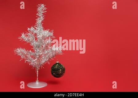 Retro tinsel Christmas tree on with bauble on a red background Stock Photo