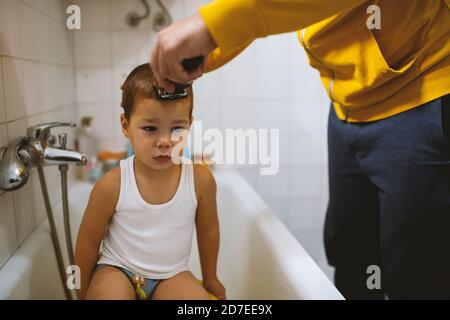 Father cutting son's hair at home during the 2020 pandemic lockdown. Covid-19 social distancing Stock Photo