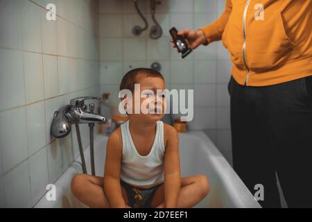 Father cutting son's hair at home during the 2020 pandemic lockdown. Covid-19 social distancing Stock Photo