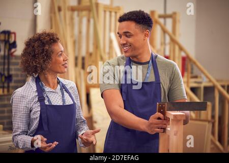 Tutor With Male Carpentry Student In Workshop Studying For College Apprenticeship Using Set Square Stock Photo