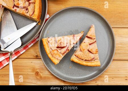 Two pieces of homemade pie with apple, cinnamon and yogurt topping on wooden table. Top view. Stock Photo