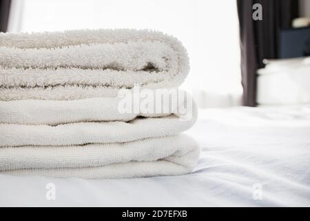 Stack of clean fluffy white towels on the bed Stock Photo