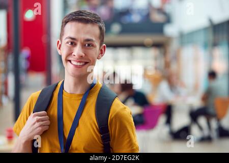 Portrait Of Smiling Male College Student In Busy Communal Campus Building Stock Photo